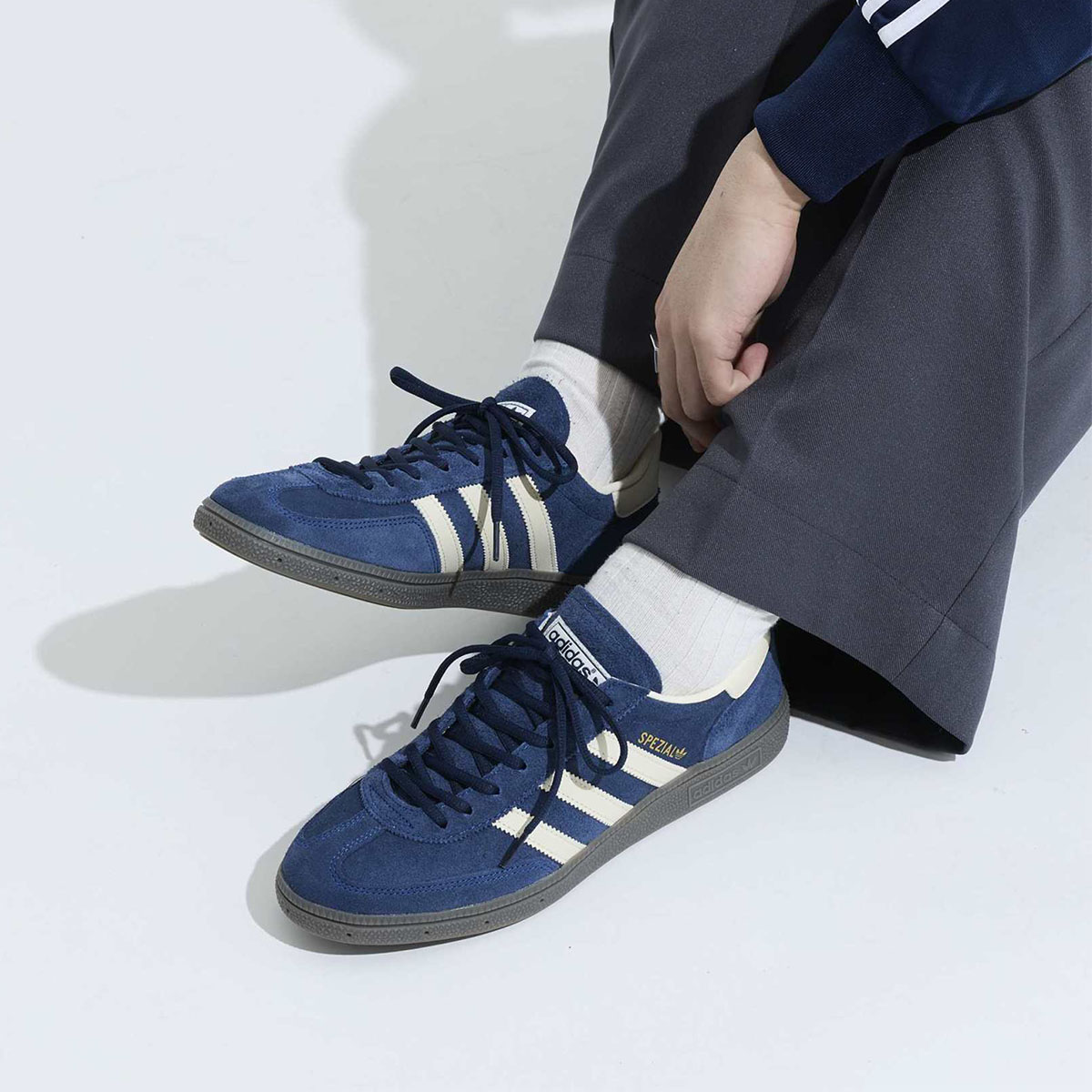 Dettaglio di scarpe sportive blu con strisce bianche indossate con calzini bianchi.