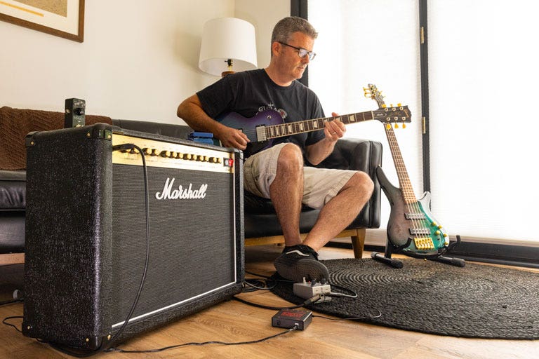 Man playing electric guitar with Marshall amplifier in home studio setup