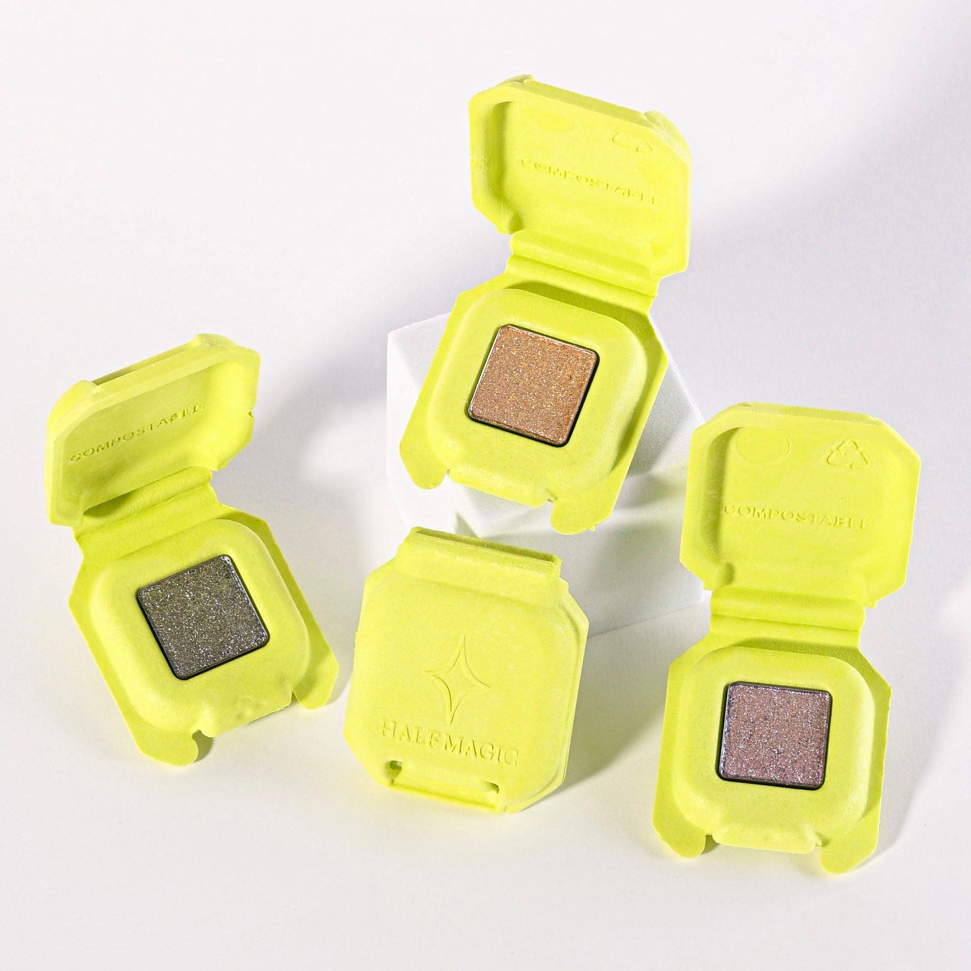 Three neon yellow compacts with bronze sparkly eyeshadow swatches open against white background